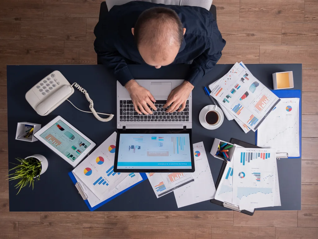 Basit Usulde Vergilendirme Nedir? 2026 Hadleri | Mavvo 32 top view business man corporate office sitting desk typing laptop working financial statistics business strategy